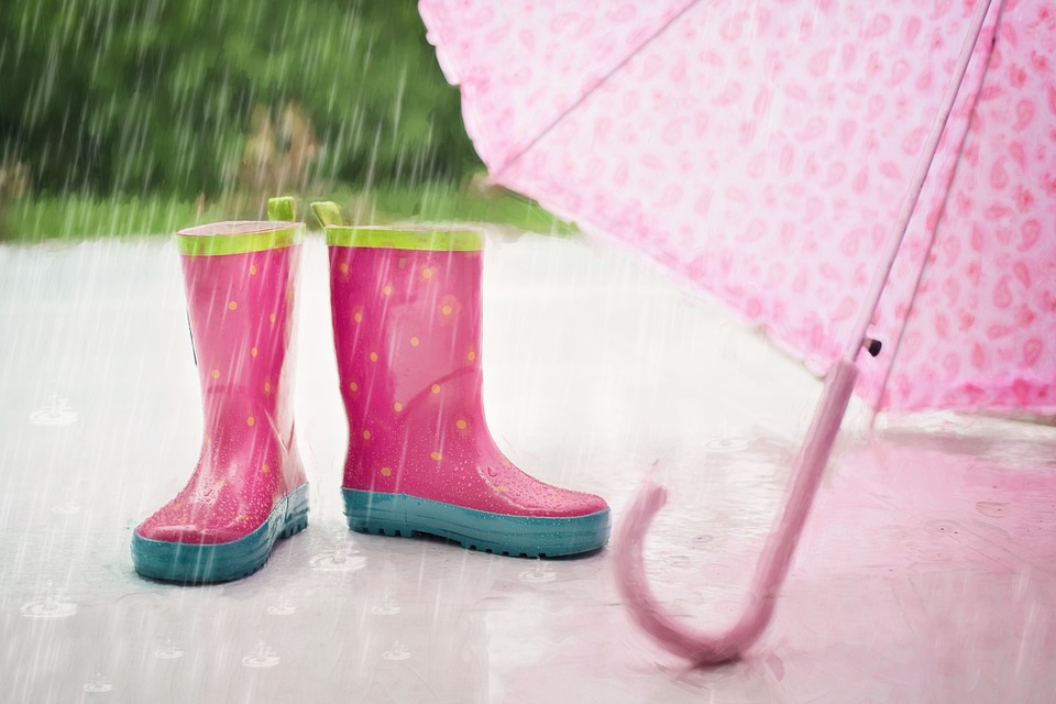 pair of rain boots and umbrella outdoors in the rain